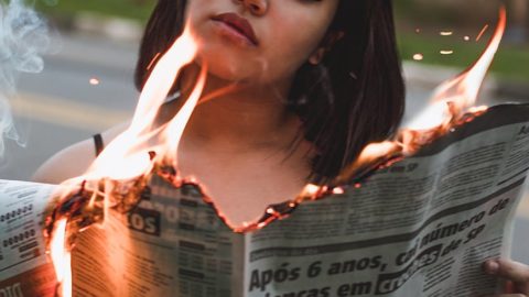 woman holding burning newspaper
