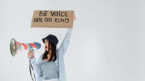 woman shouting through megaphone while holding a signage